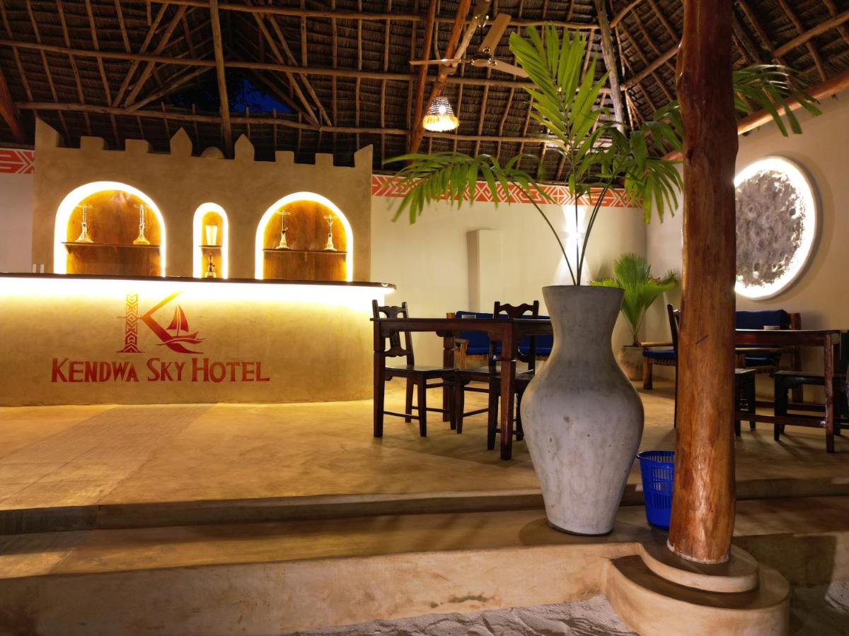 The open-sided bar and lounge under a makuti thatch roof, lit warmly at night