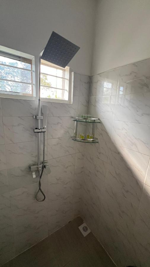 A white tiled shower with a fixed head