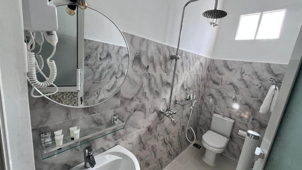 A bathroom with marble tiling, shower and toilet