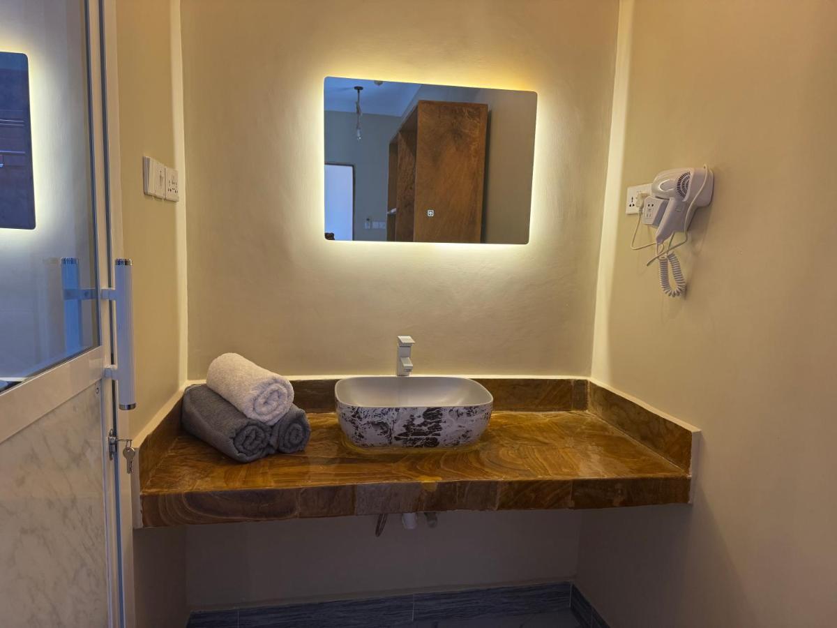 A backlit bathroom mirror above a stone vanity