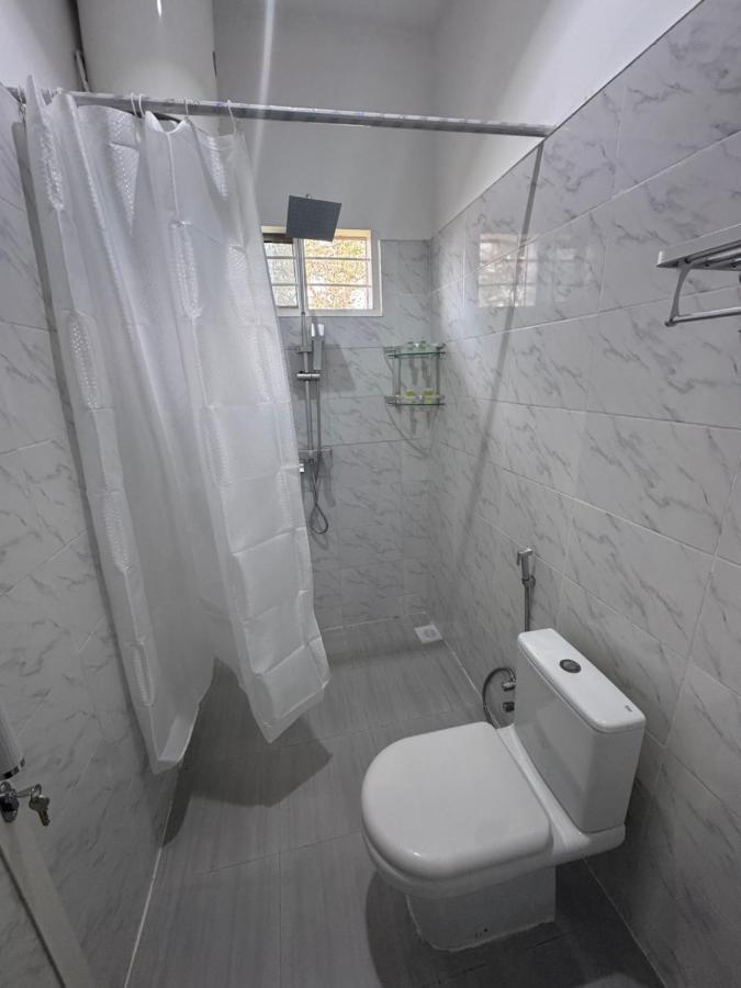 A shower behind a curtain beside the toilet