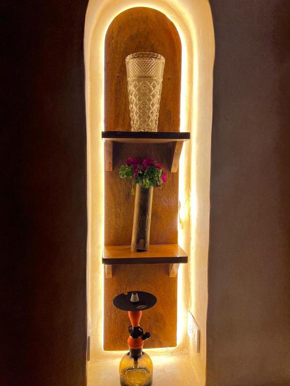 A backlit arched alcove with shelves and a vase of flowers
