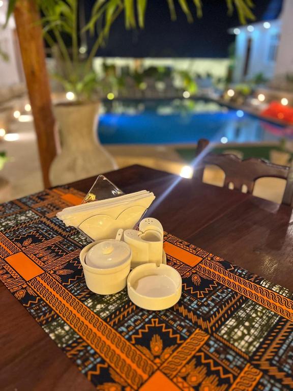 A tray of cups and a pot on a patterned table runner