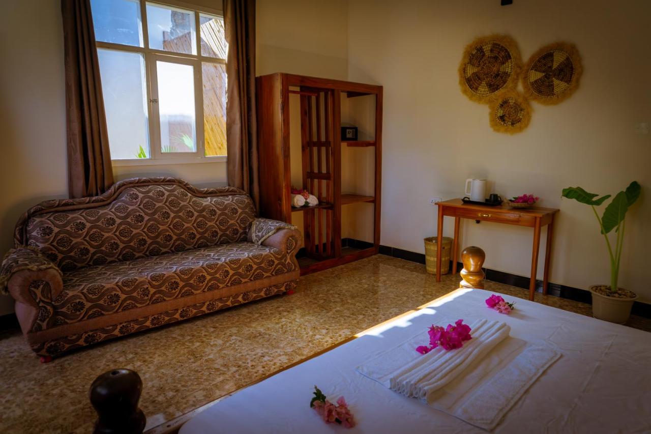 A bed dressed with flowers beside a sofa and armchair