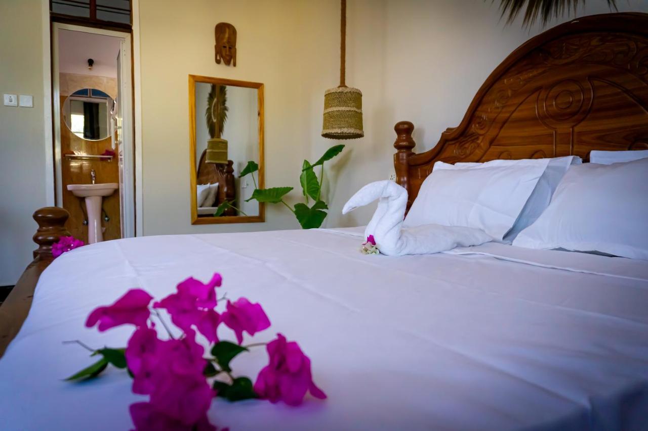 A bed dressed in white linen with bougainvillea laid across it