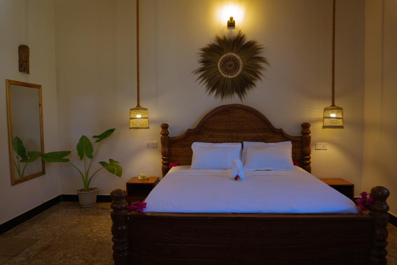 A king bed dressed in white linen beneath a carved headboard
