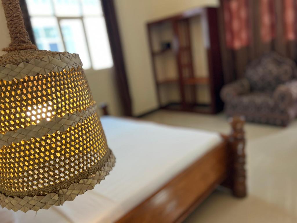 A woven pendant lampshade above a bed