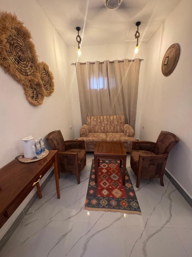 A wooden table and chairs on a patterned rug in a guest room